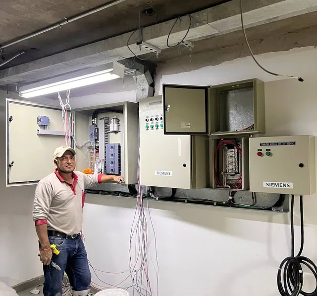 Técnico de SeviElectro junto a varios tableros de distribución abiertos, con protecciones y cableado durante una instalación