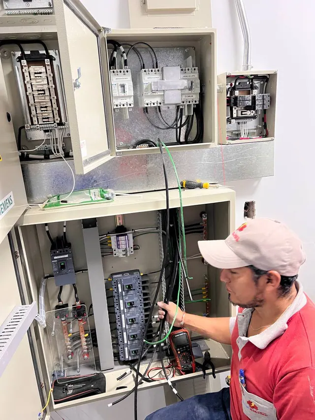 Técnico preparando el cableado de un tablero eléctrico abierto con interruptores y barras de distribución